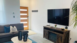A modern living room with a sofa, coffee table, TV, and a plant. - Moonlight Retreat, near Wedding Venue & Breweries (Dripping Springs)
