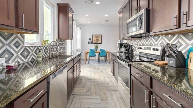 A modern kitchen with dark wood cabinets, granite countertops, and a herringbone tile backsplash. - Moonlight Retreat, near Wedding Venue & Breweries (Dripping Springs)