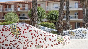 A hotel with a tiled mosaic wall, palm trees, and a multi-story building with balconies. - Les Demeures de la Massane ST6C (Argeles-sur-Mer)