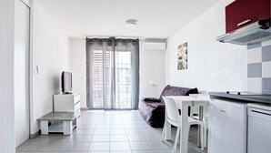 A modern kitchen with white appliances, a dining area with a table and chairs, and a living area with a sofa and a TV. - Les Demeures de la Massane ST6C (Argeles-sur-Mer)