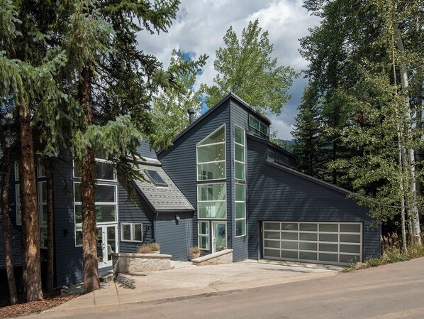 A modern two-story house with a garage, surrounded by tall trees. - Rockledge 325 | 4BR Vail Luxury Home Near Ski Slopes (Vail)