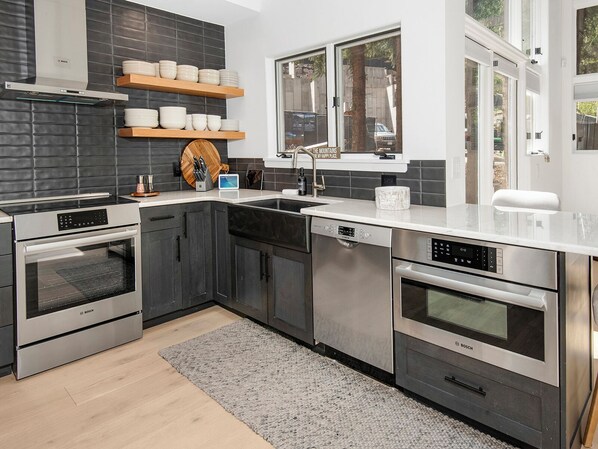 A modern kitchen with Bosch appliances, dark cabinetry, and a large window overlooking a garden. - Rockledge 325 | 4BR Vail Luxury Home Near Ski Slopes (Vail)