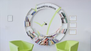 A circular bookshelf with books arranged in a spiral pattern, two green chairs, and three framed motivational quotes on the wall. - Les Demeures de la Massane 2P4S (Argeles-sur-Mer)