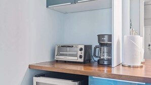 Eine Küchenzeile mit Toaster, Kaffeemaschine und Papierhandtuchspender.