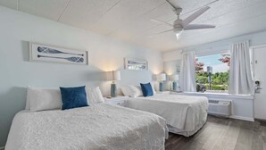 Ein Hotelzimmer mit zwei Betten, einem Deckenventilator und einem Fenster mit Vorhängen.