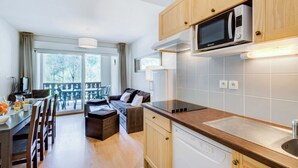 A compact kitchen with wooden cabinets, a microwave, and a built-in dishwasher.