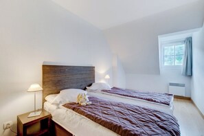 Ein Hotelzimmer mit zwei Betten, einem Holz-Kopfteil, Nachttischlampen und einem Fenster mit Vorhängen.