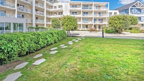 A multi-story hotel with balconies, a grassy courtyard, and a clear sky.