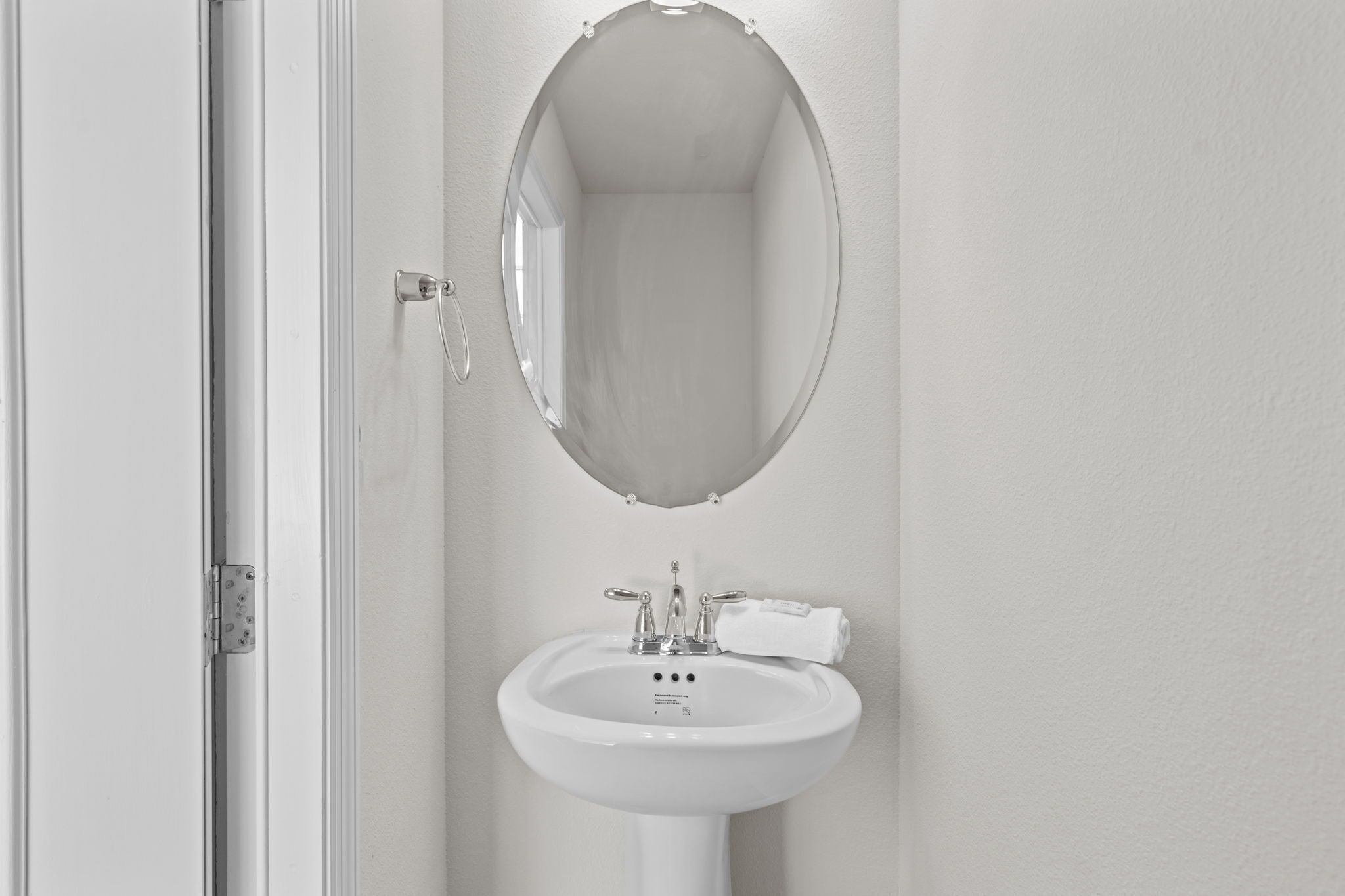 A bathroom with a white sink, a mirror, and a towel hanging on the wall.
