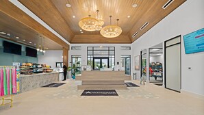 A modern hotel lobby with a reception desk, a staircase leading to the upper floor, and a sign for 'Windsor'.