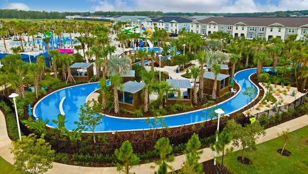 A resort with a large pool, palm trees, and modern buildings.