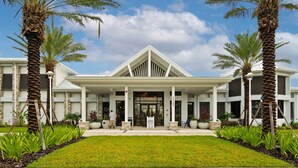 A modern hotel with a white facade, a central entrance, and palm trees.