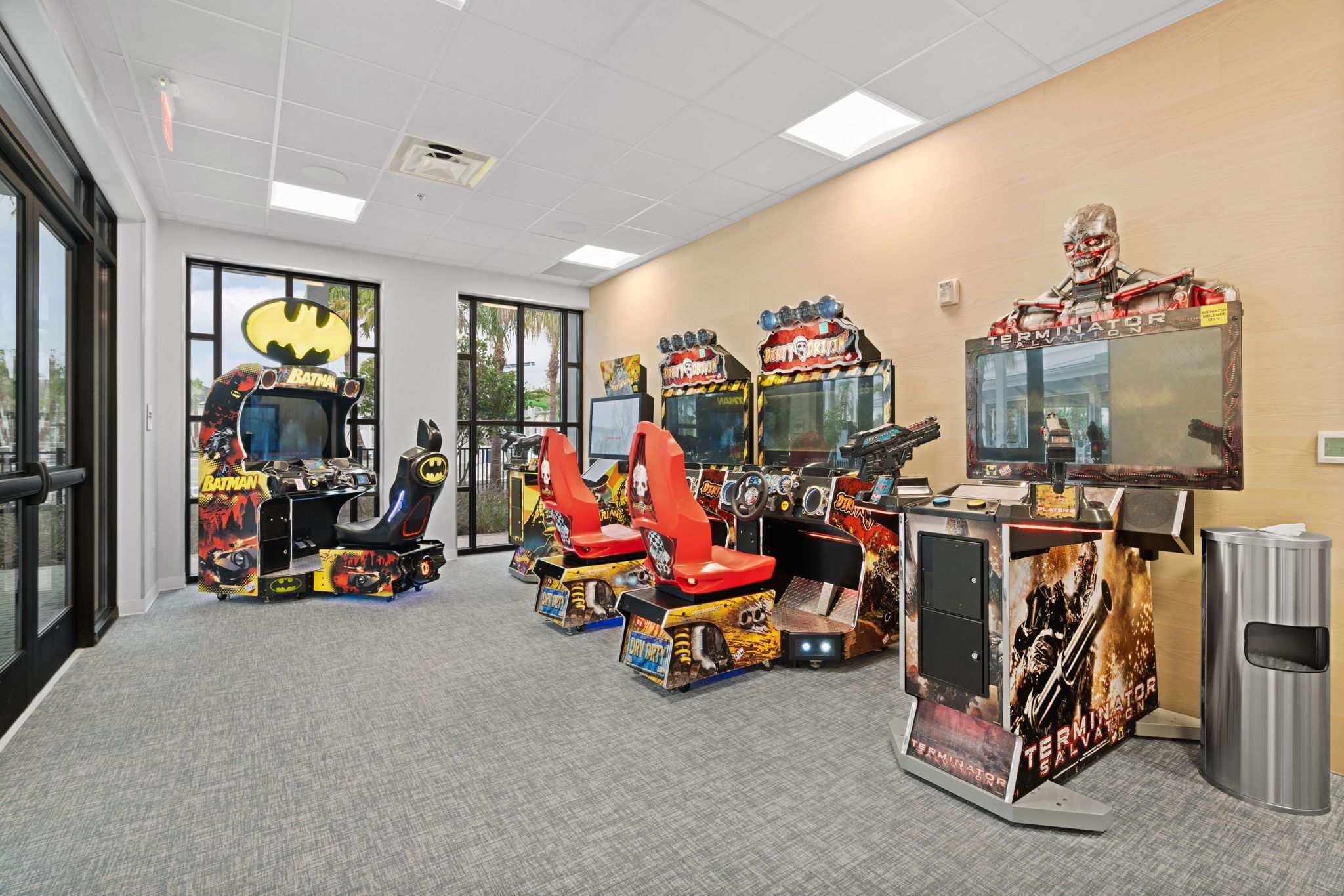 A room with arcade games, including Batman and Terminator, and a trash bin.