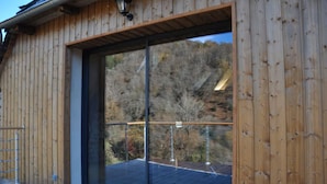 A wooden building with a large sliding glass door leading to a deck.