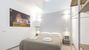 Ein modernes Hotelzimmer mit einem Bett, einem am Wand montierten Fernseher, der das Kolosseum zeigt, und einer vertikalen Leuchtafel.