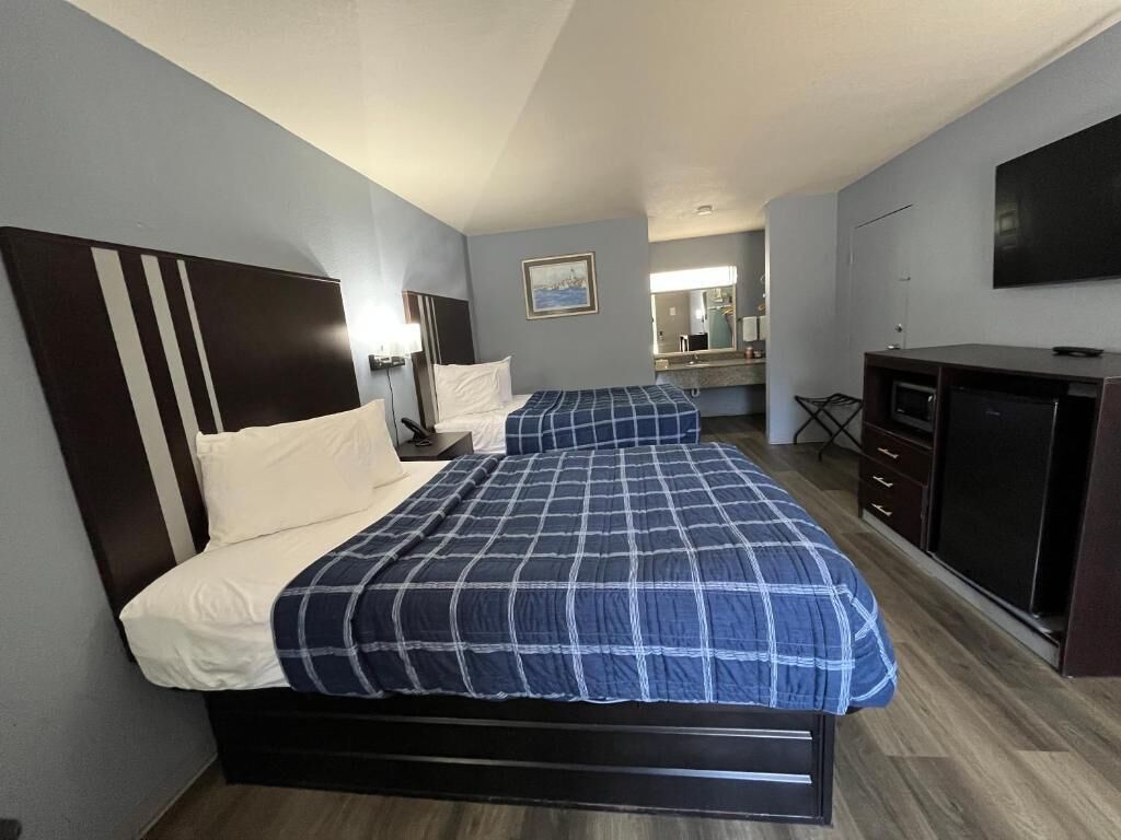 A hotel room with a bed, a desk, a TV, and a mirror.