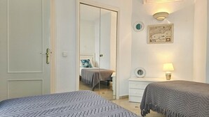 A bedroom with two beds, a dresser, a mirror, a map on the wall, and a door with a handle. - Seaview apartment in El Porton Calahonda (Sitio de Calahonda)