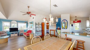 A spacious living room with a large TV, comfortable seating, and a dining area with a tiled table. - 4BR Soundview | Deck | Washer/Dryer (Duck)