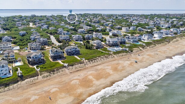 An aerial view of a coastal residential area with houses, a beach, and a lighthouse. - 4BR Soundview | Deck | Washer/Dryer (Duck)