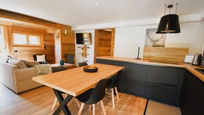 A modern kitchen with a wooden table and chairs, a black countertop, and a ceiling light.