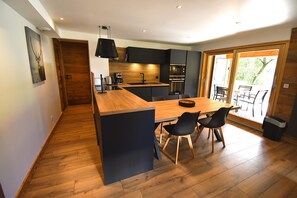 A modern kitchen with a wooden island, black chairs, and a dining table.
