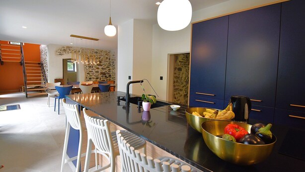 Una cocina moderna con una isla central, taburetes de bar y un frutero.