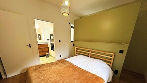 Un dormitorio con cama, cabecera de madera y una puerta que da al baño.