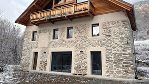 Un edificio de piedra con balcón de madera, varias ventanas y techo inclinado.