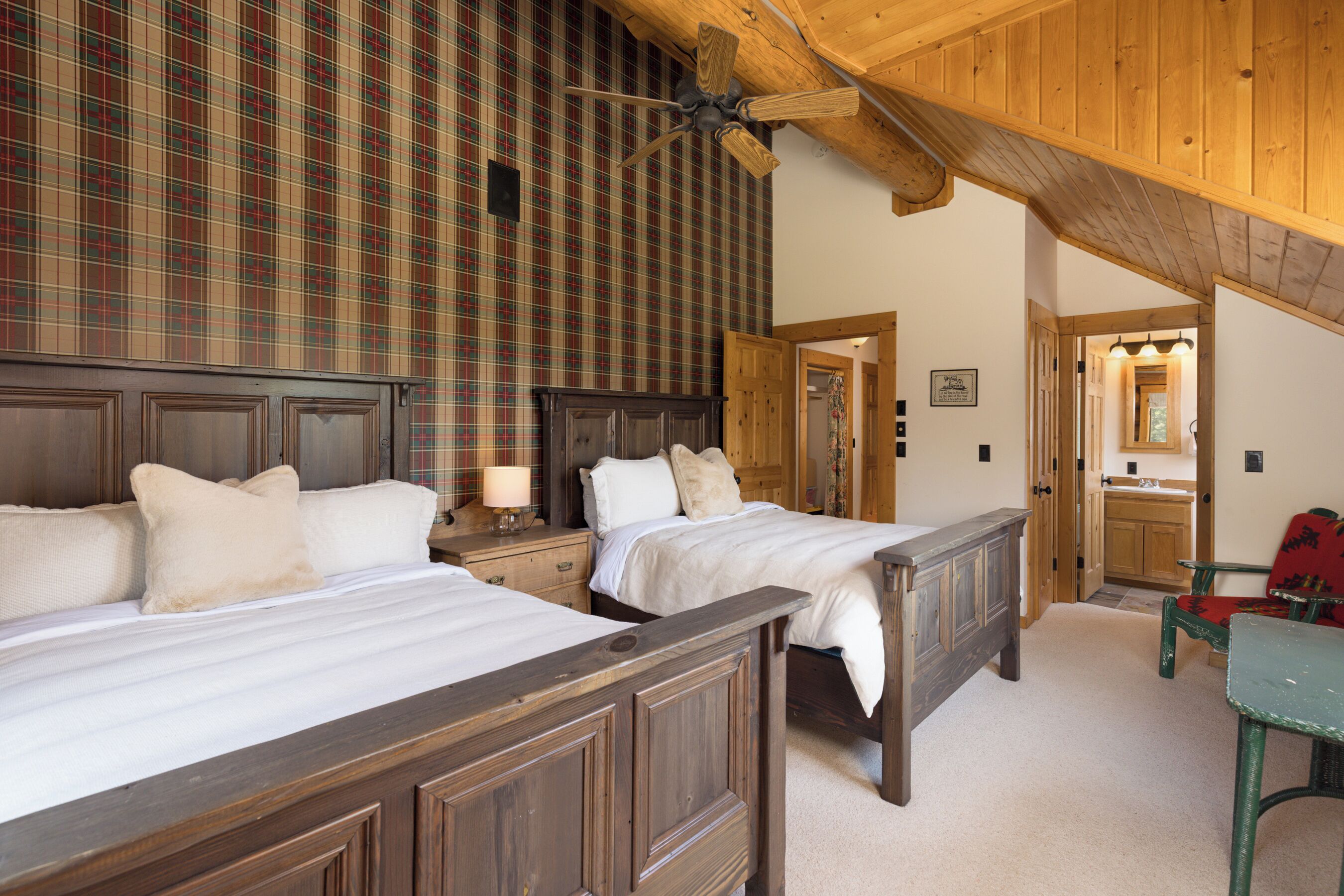 A bedroom with two wooden beds, a plaid-patterned wall, and a wooden ceiling.