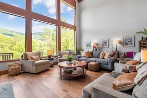 Un salon spacieux doté de grandes fenêtres, d’une cheminée et d’un coin salon confortable.