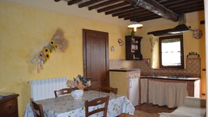 A dining area with a table set for two, a wooden door, and a kitchen with a window.