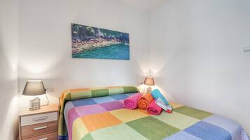 A bedroom with a bed, a nightstand, a lamp, and a painting on the wall.