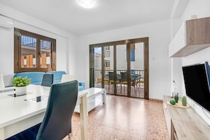 Una sala de estar moderna con comedor, televisor y puerta corrediza de vidrio que da a un patio exterior.