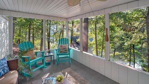 Une véranda abritée avec deux fauteuils Adirondack turquoise, une petite table et un fauteuil en osier.