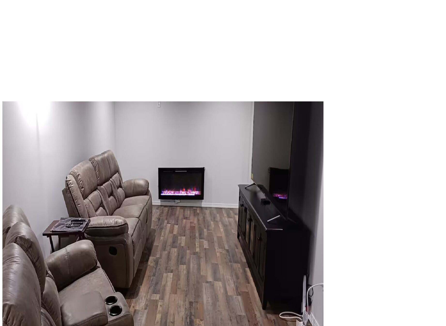 A living room with a leather sofa, a flat-screen TV, and a fireplace.