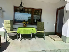 Eine Terrasse mit zwei Stühlen, einem Tisch und einem Blumentopf.