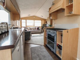 Cucina camper compatta con fornello, forno e tostapane. Nell'area soggiorno, divano e tavolo da pranzo.