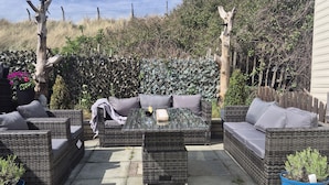 A patio area with wicker furniture, a glass-top table, and potted plants. - Caravan 596 (Prestatyn)