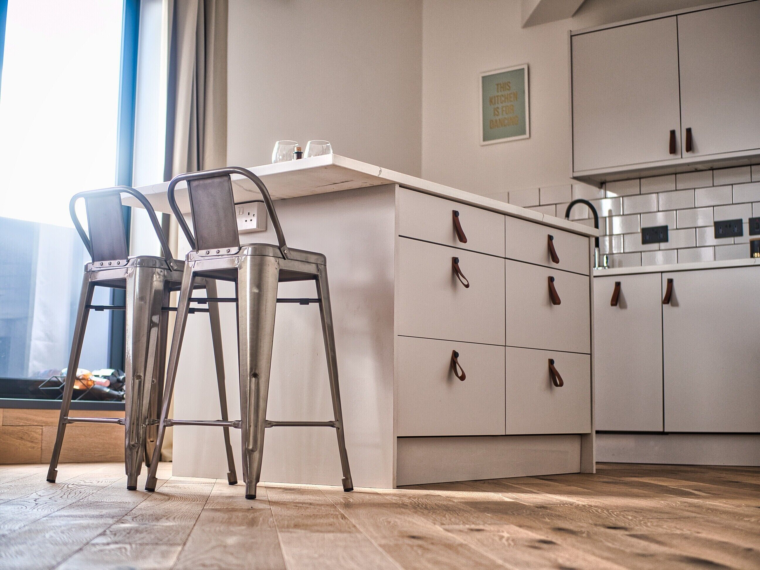Une cuisine moderne avec deux tabourets de bar, un plan de travail et des placards.