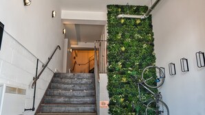 Eine Treppe mit Metallgeländer, einem am Wand montierten Fahrradständer und einer vertikalen Begrünung.