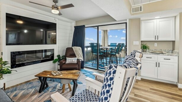 A modern living room with a fireplace, a sofa, a coffee table, and a dining area with chairs.