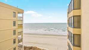 A view of a beach from a building with multiple balconies overlooking the ocean.