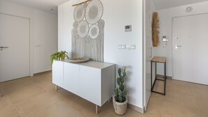 A modern interior with a white console table, a cactus plant, and a wall art piece. - Sunrise Heights 2455 Sea View (Manilva)