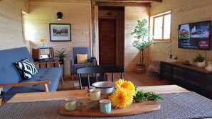 Una sala de estar acogedora con un sofá, una mesa de comedor con una bandeja de flores y un televisor en la pared.