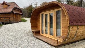 Una cabaña de madera con techo curvo, puertas de cristal amplias y una terraza de madera.