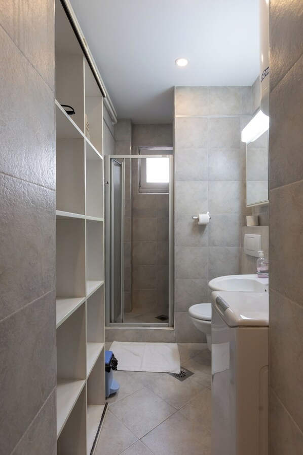 A modern bathroom with a shower, toilet, and sink, featuring tiled walls and a glass shower enclosure. - City View Apartments (Belgrade)