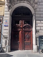 Una puerta doble de madera con tallas elaboradas y una reja metálica encima.