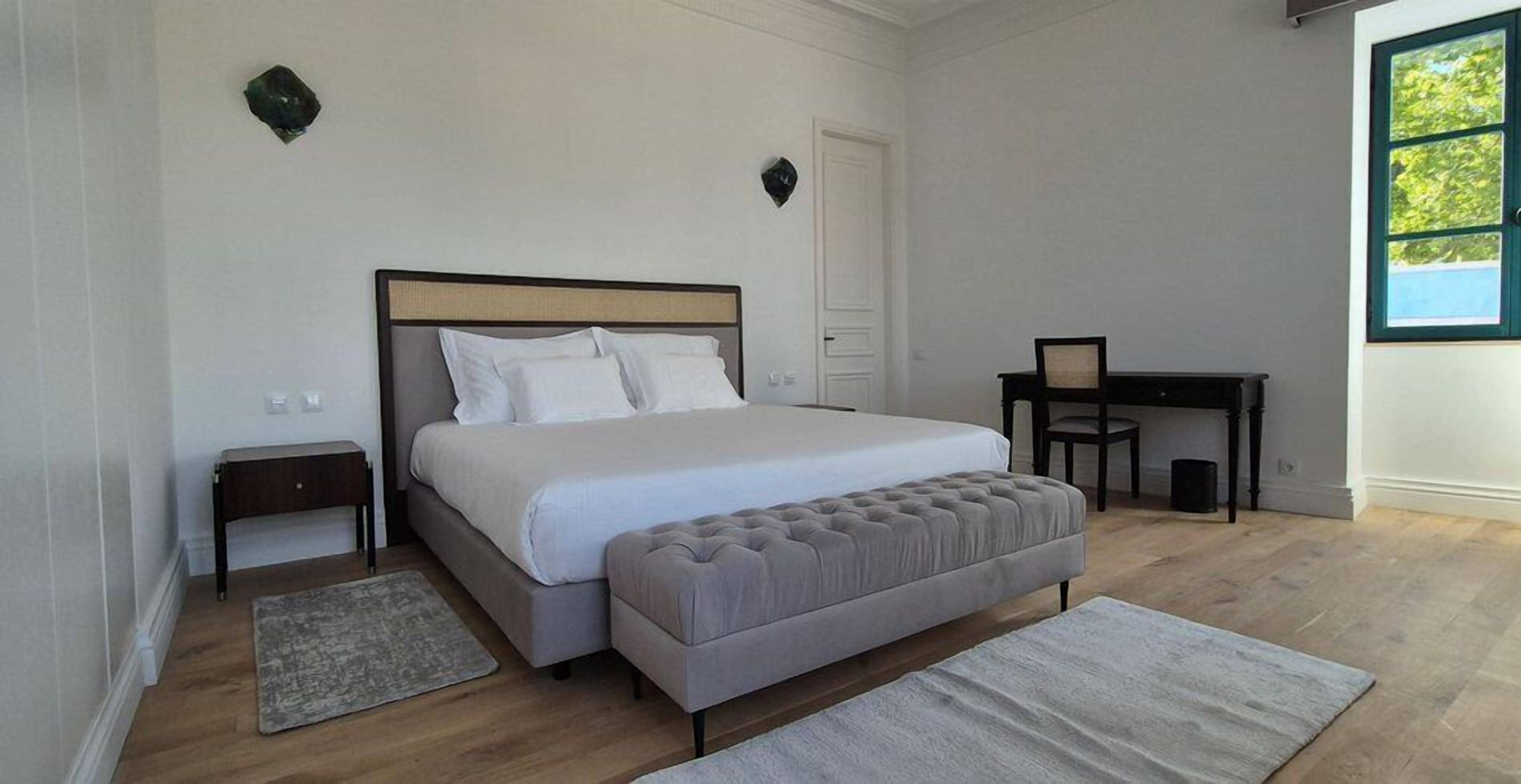 A bedroom with a large bed, a desk, and a window.