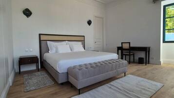 A bedroom with a large bed, a desk, and a window.