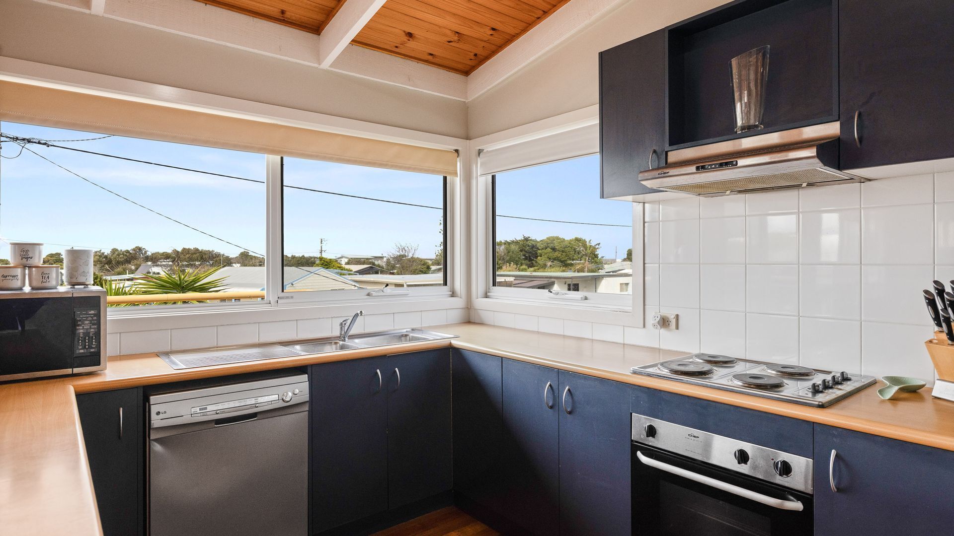 A modern kitchen with dark cabinets, a dishwasher, a stove, and a microwave.